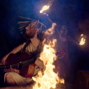 Apollon (Julian Allescher) mit Gitarre am Lagerfeuer.